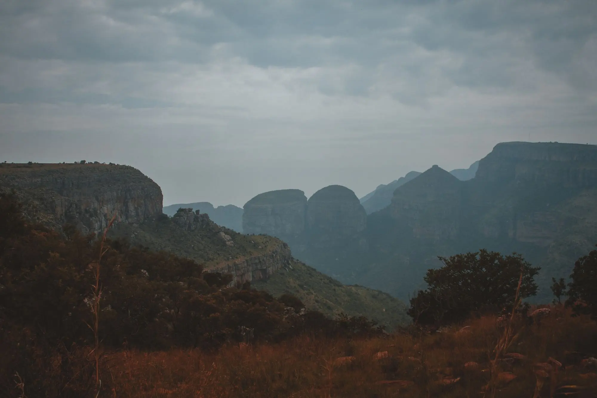 Cliffs and green valleys on the Panorama Route in evening mist